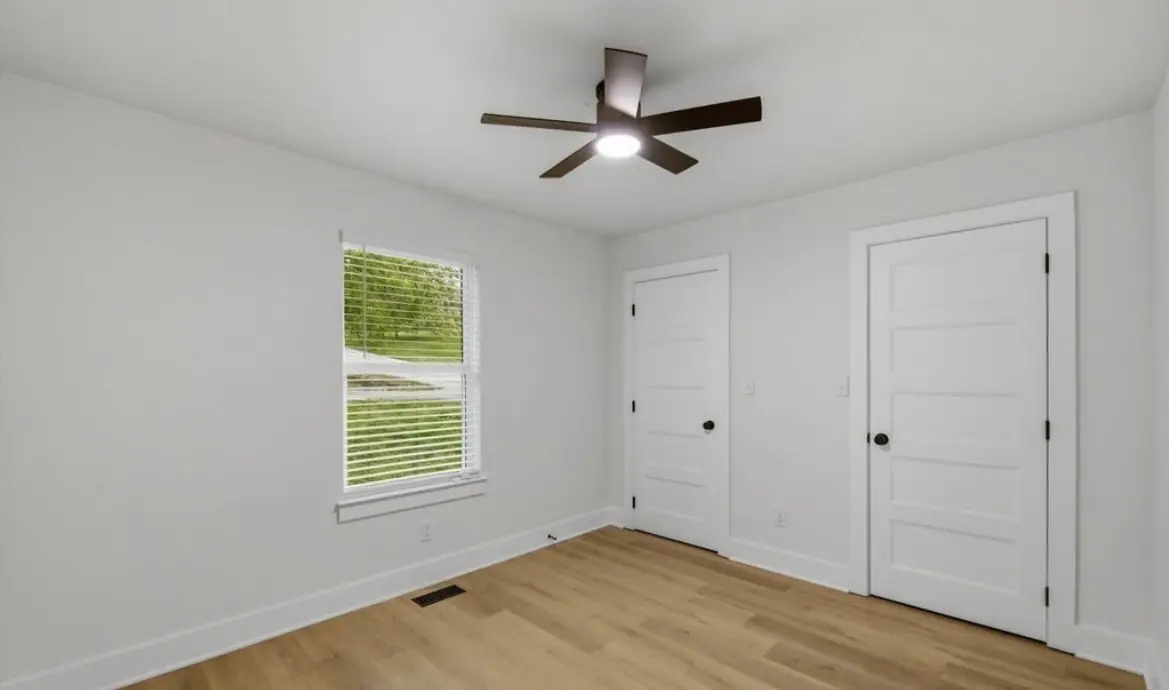 Bedroom with white five-panel doors, a black ceiling fan, and light wood-look plank flooring