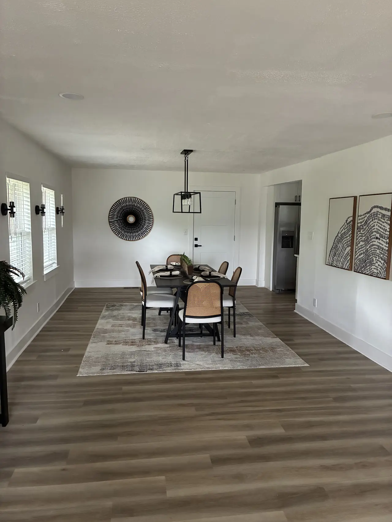 Dining room with a black pendant light, wall sconces, and wood-look plank flooring after a full gut renovation
