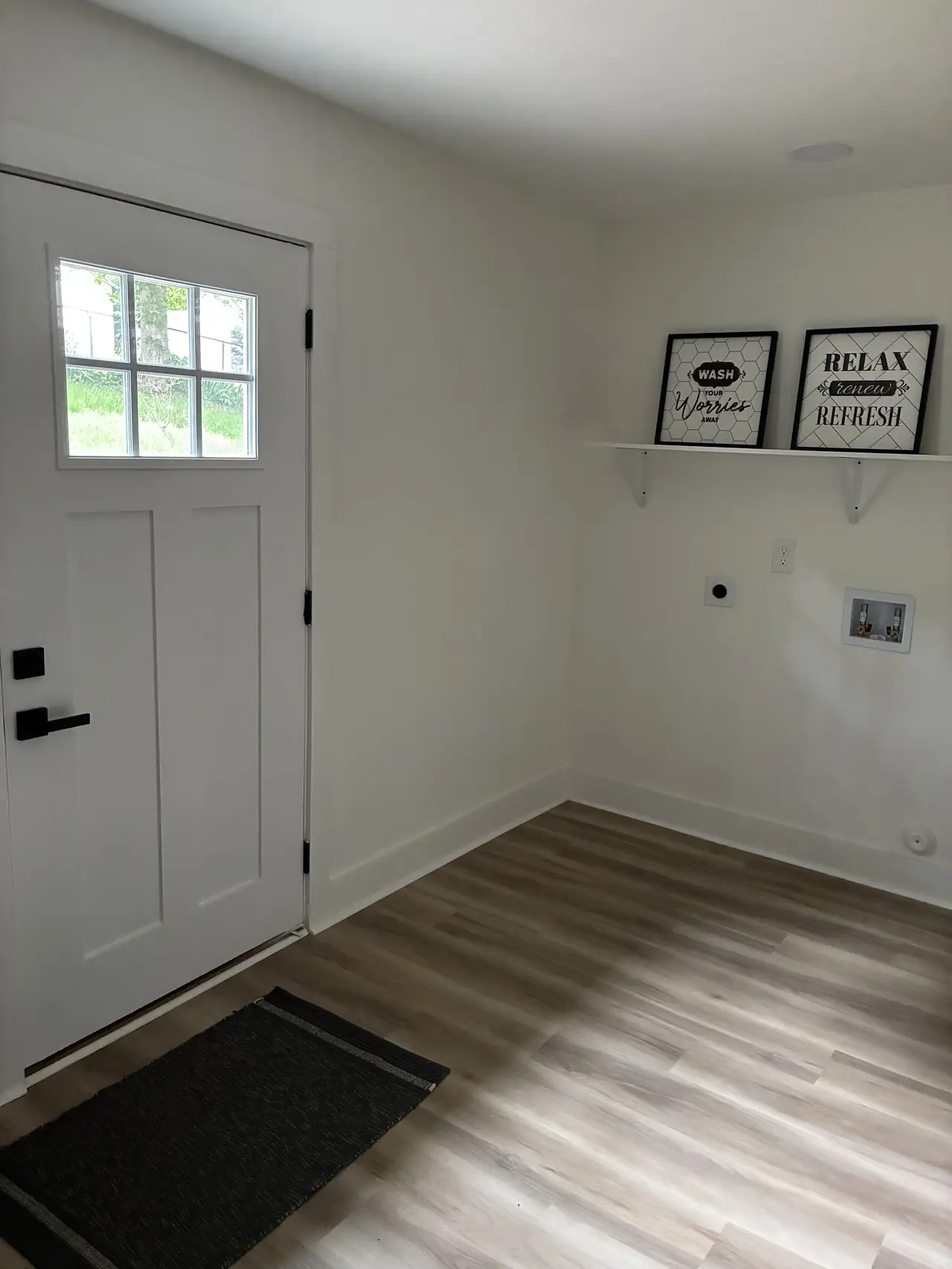 Entry and laundry area with a white craftsman-style door, a wall shelf, and washer hookups