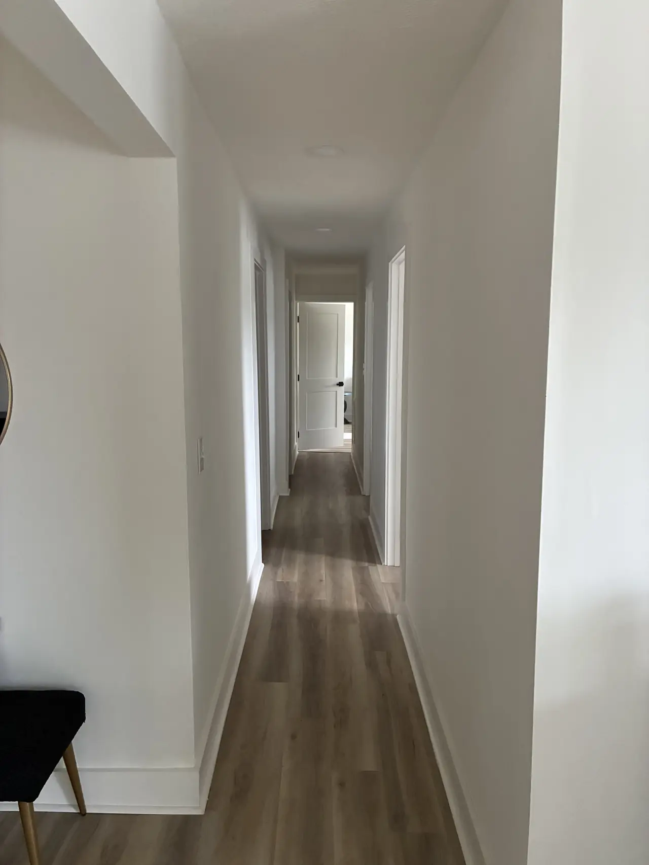 Renovated hallway with white walls, white doors, a recessed light, and wood-look plank flooring