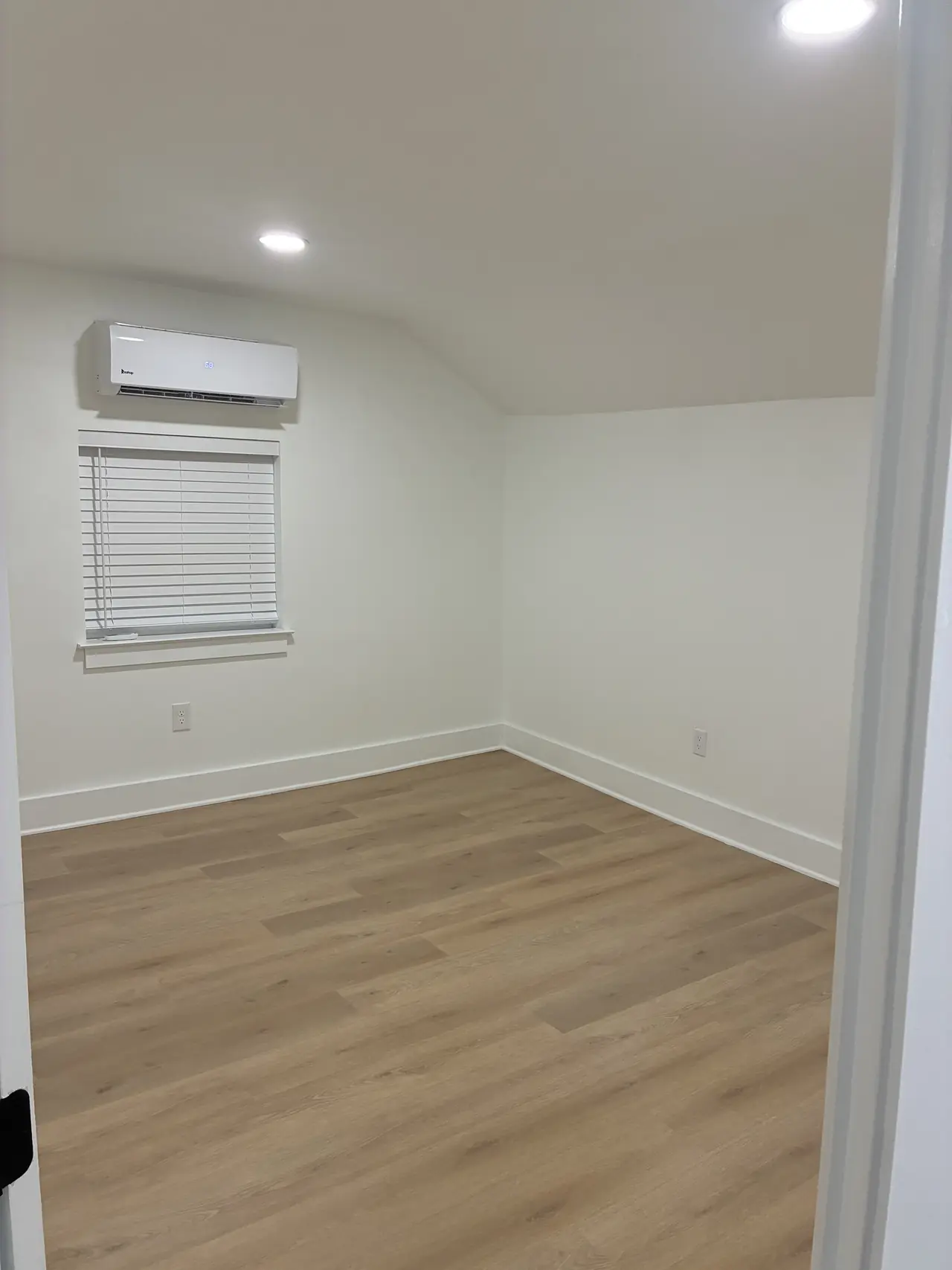 Upstairs bedroom with a sloped ceiling, a ductless mini-split, recessed lights, and wood-look plank flooring